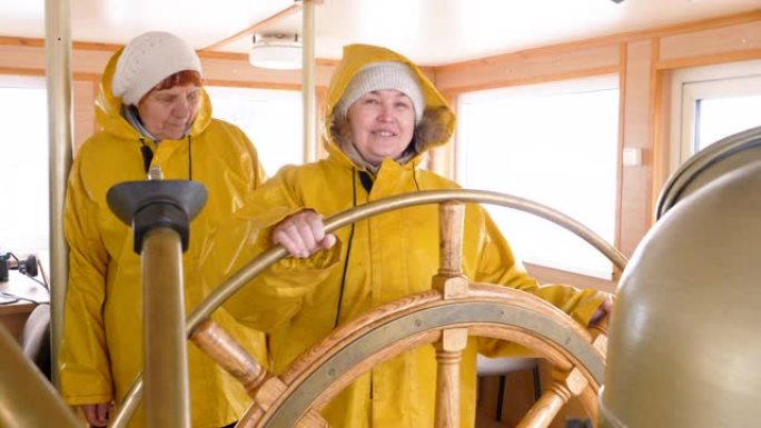 微笑的女船长转动方向盘浮动船。航行船上驾驶舵手的帆船女船长。帆船和航运概念。