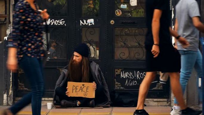 无家可归的人拿着 “和平” 纸板在拥挤的街道上乞讨