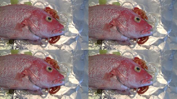 红鲷鱼-锡箔上的西红柿，橄榄和洋葱上的生鱼