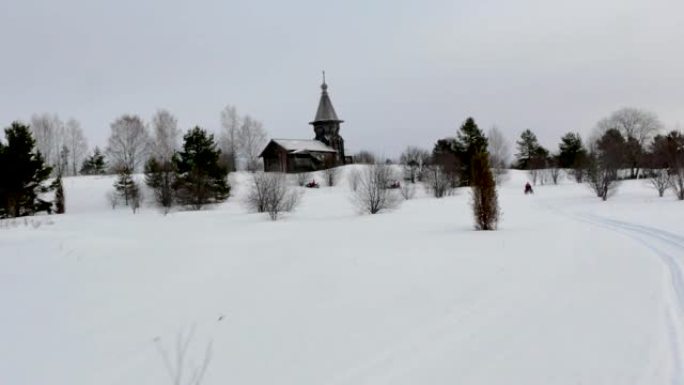 雪地车司机穿过雪谷对着老教堂