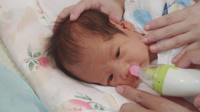 新生儿; 用吸气器清洁婴儿的鼻子。