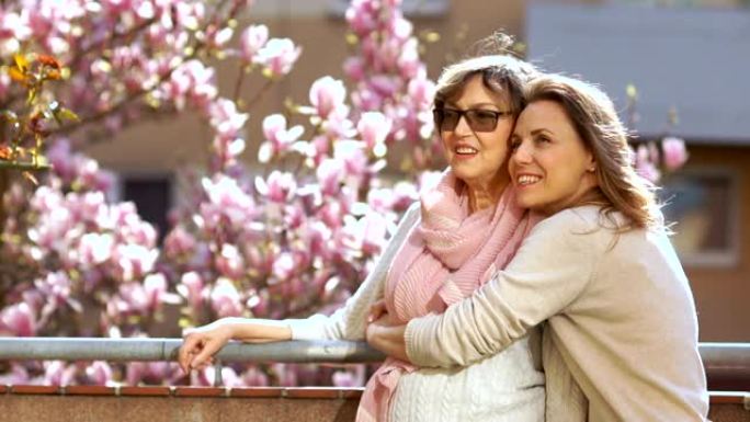 母亲节。两个美丽的女人被拍到在明亮的春天天空和一片盛开的玉兰和樱花