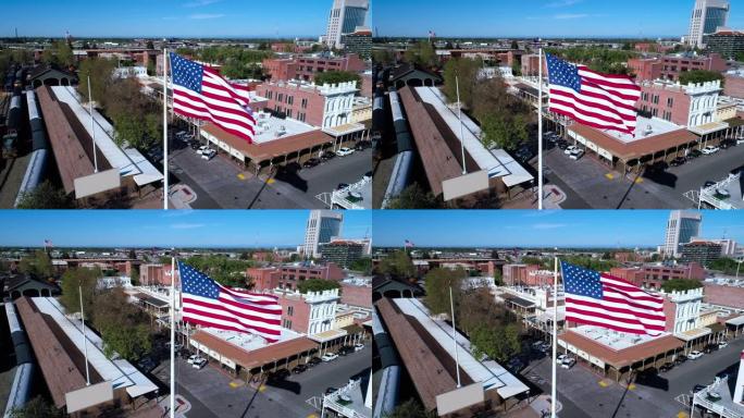 老萨克拉门托和遥远的萨克拉门托市中心前飘扬的美国国旗。无人机低空视频与轨道摄像机运动。