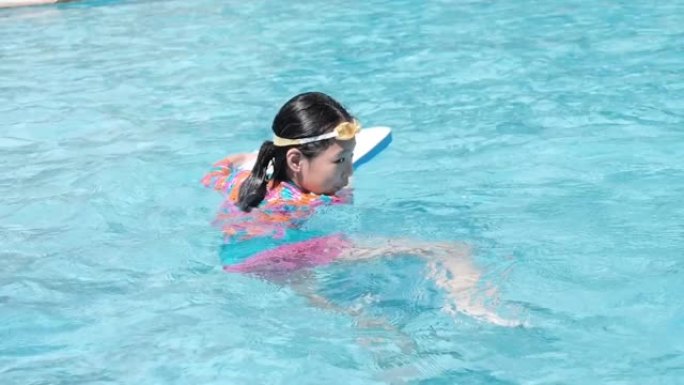 亚洲女孩学习游泳池慢动作游泳。