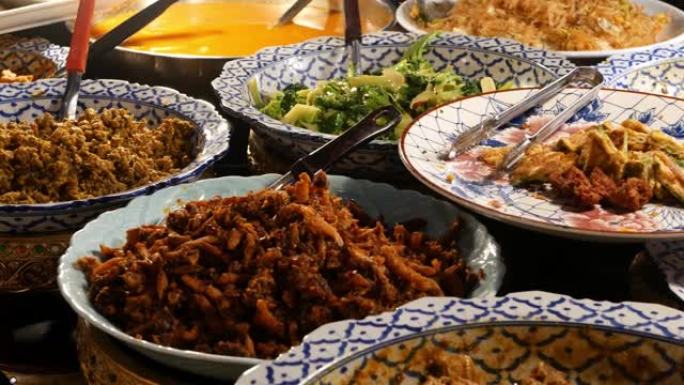 摊位上有各种亚洲菜肴的碗。晚上，一碗各式各样的传统泰国菜放在街头小餐馆的摊位上。东方夜市美食广场。