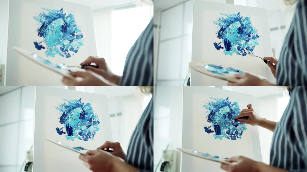 放大创意女性在画布上用丙烯酸颜料和调色板刀绘制抽象图片的照片