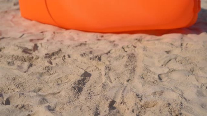 一个年轻女子在热带海滩上坐在充气沙发上的慢镜头。暑假概念