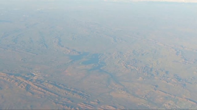 来自飞机窗口的POV显示红色地球山脉和湖泊中屏