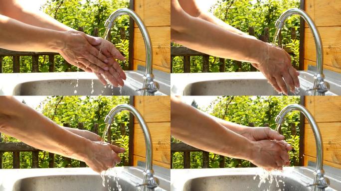 夏天阳光明媚的日子，女人在花园里的室外水龙头在自来水下洗手，使用干净的水和卫生概念