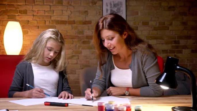 年轻母亲和女儿画画和共度时光的特写肖像。妈妈教女孩如何画画