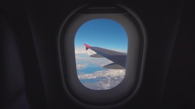 美丽的云和飞机的翅膀从窗户上飞来，有着美丽的蓝天。4K