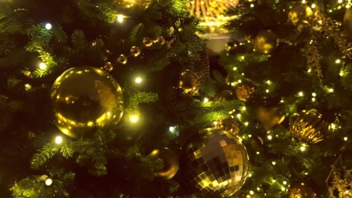 圣诞树的树枝上有金色和花环的圣诞球，特写镜头。