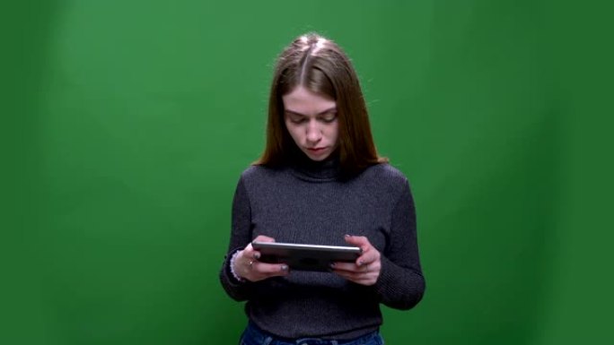 年轻的金发女商人用心工作，平板电脑隔离在绿色chromakey背景。