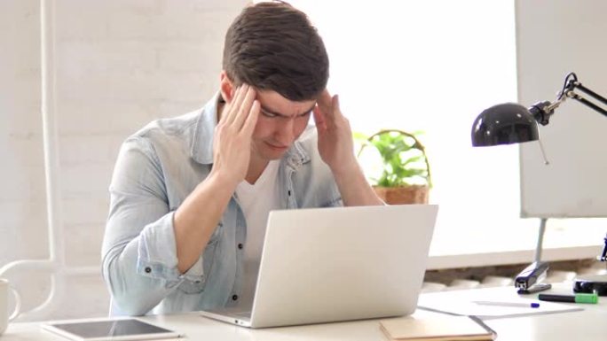紧张的年轻人在笔记本电脑上工作时头疼