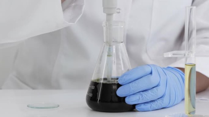 在带有玻璃滴管和一个碗的实验室中使用药物CBD油的科学家的特写