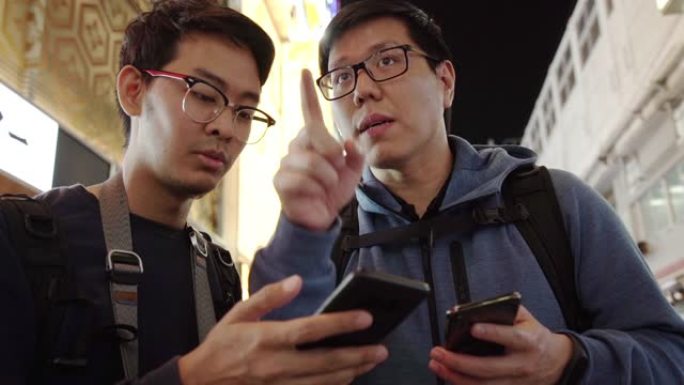 两个旅游朋友用智能手机谈论方向。