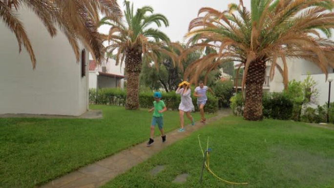 父母和孩子在雨中在院子里奔跑