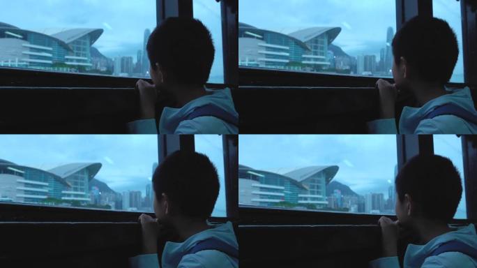 亚洲男孩坐渡轮，看着香港的天际线