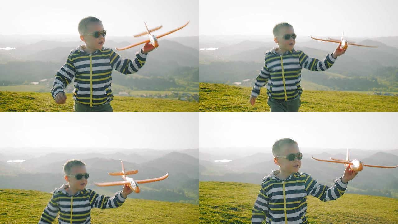 快乐的旅行者男孩在公园的晴天玩飞机玩具。4k慢动作视频。日落时，孩子在山顶上奔跑。宇宙边缘之旅