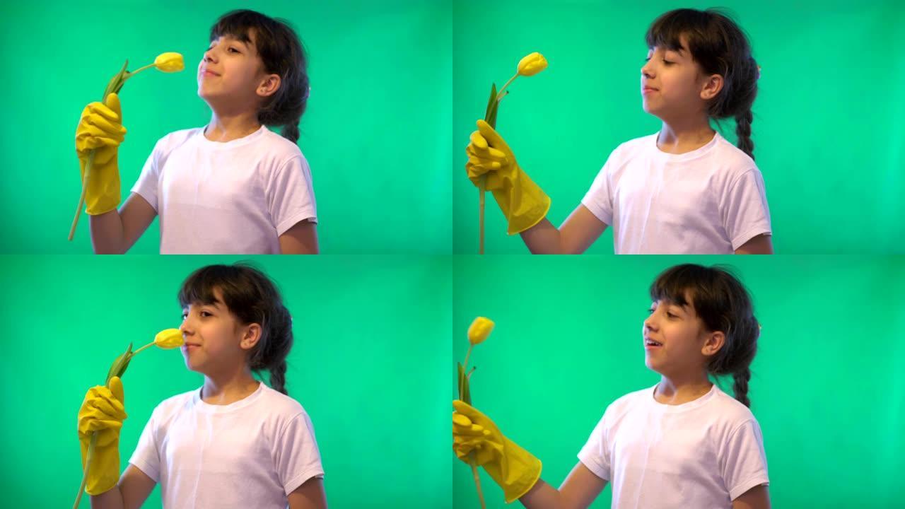 绿色背景上戴着黄色手套的女孩嗅着黄色郁金香
