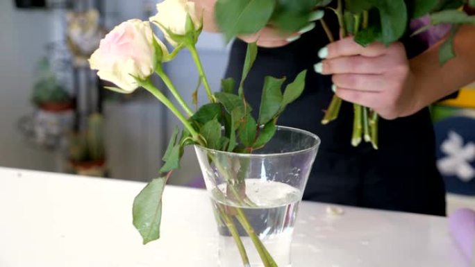 女专业花店把玫瑰放在花店的花瓶上，双手特写。