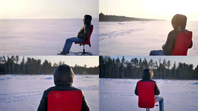 在雪场背景上的红色椅子上，独自一人穿着保暖外套和兜帽的商人的镜头周围盘旋。