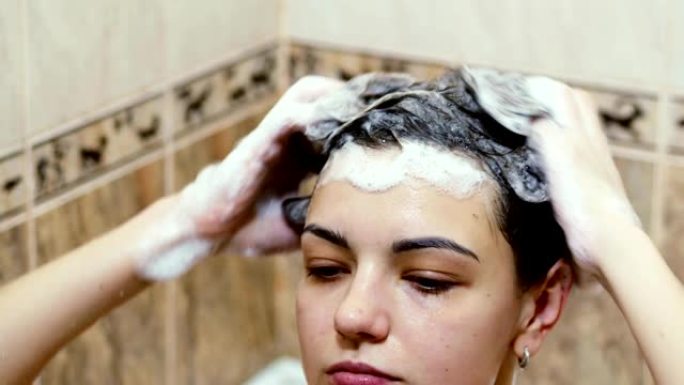 美丽的女人用洗发水洗长头发的特写