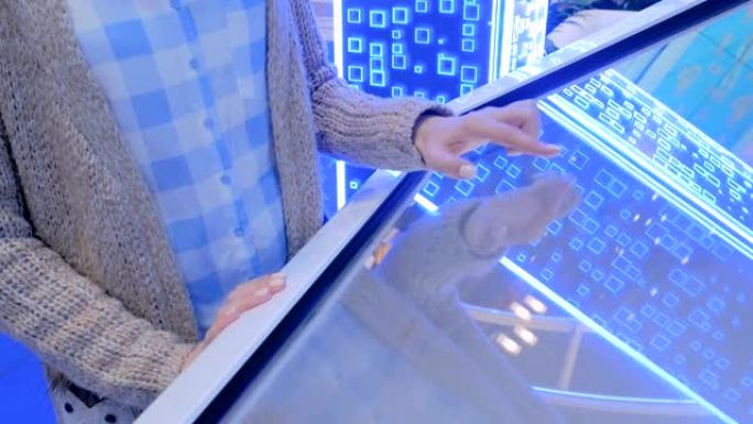 在技术展览会上使用交互式触摸屏显示器的女人