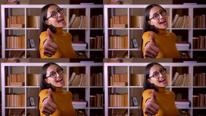 快乐而高兴的黑发女老师在图书馆示意竖起大拇指以示喜欢和尊重。