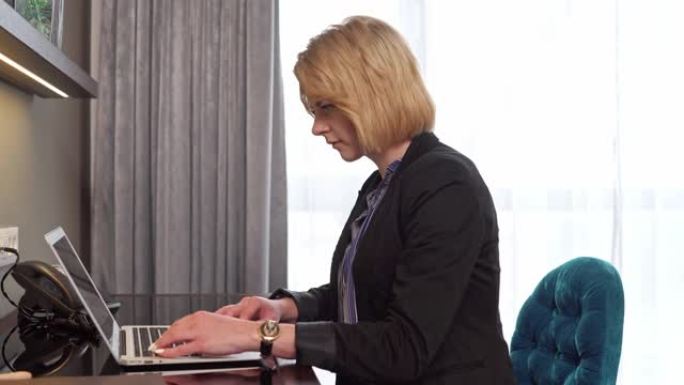 成熟的金发女人在笔记本电脑上做会议的演示