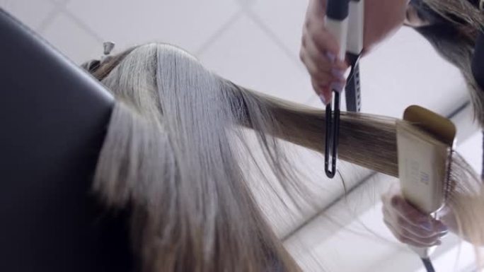 理发师在美容院为一个黑发女孩做头发层压