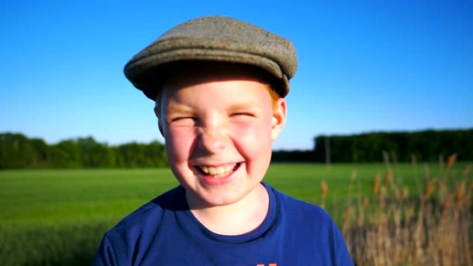 帽子里快乐男孩的肖像嘲笑乡村环境。可爱的英俊宝贝带着快乐的微笑看着镜头。脸上带着高兴的表情特写男孩子