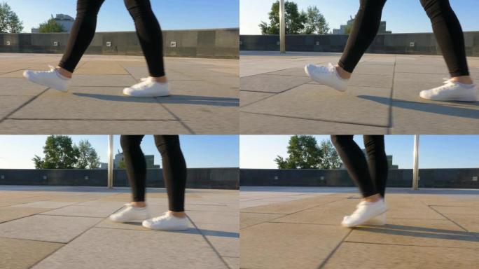 穿着白鞋的女人的腿正沿着干净，空旷的人行道行走。
