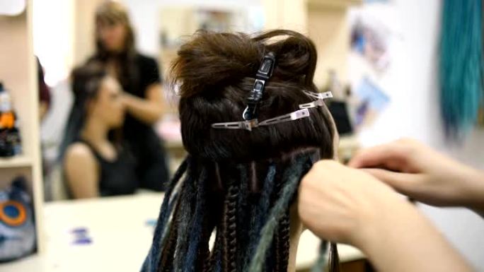 女孩理发师在沙龙里编织辫子客户