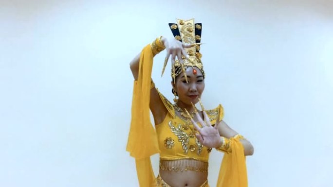 美丽的亚洲女人穿着传统的泰国黄色连衣裙，用手与长指甲修指甲跳舞