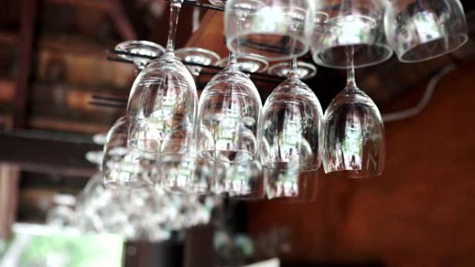 一组空酒杯悬挂在酒吧架上方。