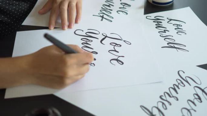 一个年轻女子使用刻字技术在纸上写字的特写镜头。她写爱自己
