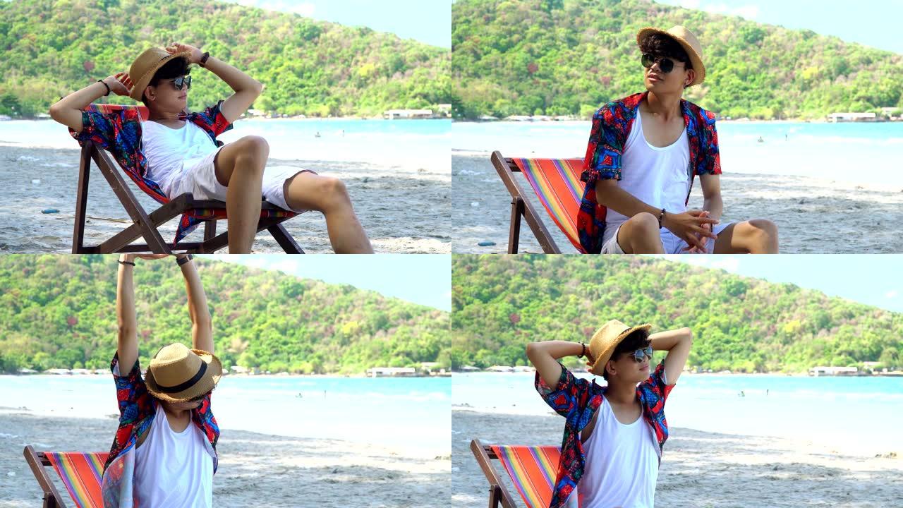 穿着休闲服和太阳玻璃的4k中号射击年轻成年亚洲男子旅行者感到自由，在暑假度假旅行中，躺下坐在热带岛屿