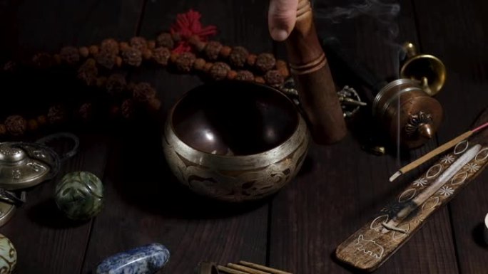 铜唱歌碗和一个男人的手牵着木棍在上面，替代医学和冥想