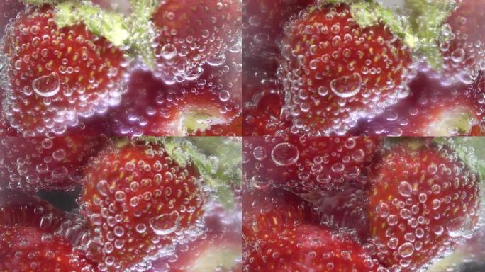 玻璃苏打水配冰块和草莓，中心屏幕。泡沫上升。