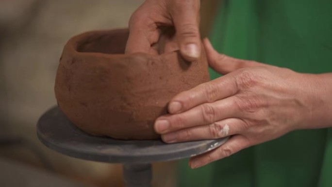 陶工手在旋转支架上成型和成型陶瓷锅的特写镜头。在工作室工作的艺术家。传统雕刻概念