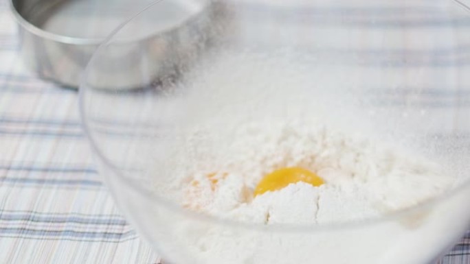 在面包制作过程中，近距离蛋黄落在面粉上的慢动作