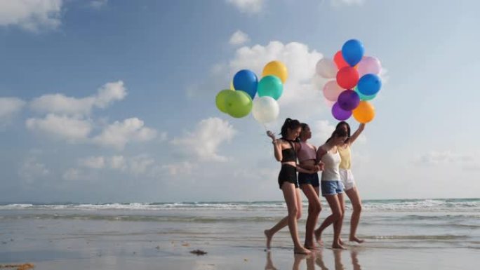 亚洲女子组合带着气球一起在海边海滩散步。青年亚洲快乐情感和周年庆典。4k分辨率和慢动作。