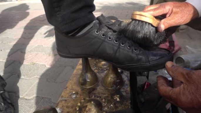 一位老人在街上打磨时尚鞋子的特写镜头