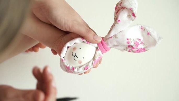 妇女和儿童的手握着为复活节兔子装饰的鸡蛋，用记号笔画兔子的脸。