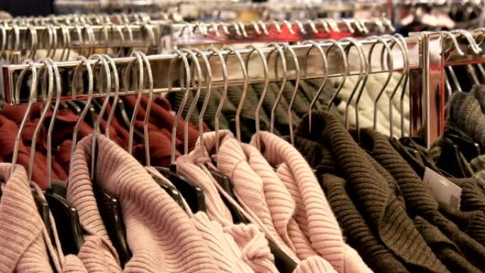 服装店购物中心或商场的衣架上悬挂着大量不同颜色的新款保暖时尚毛衣