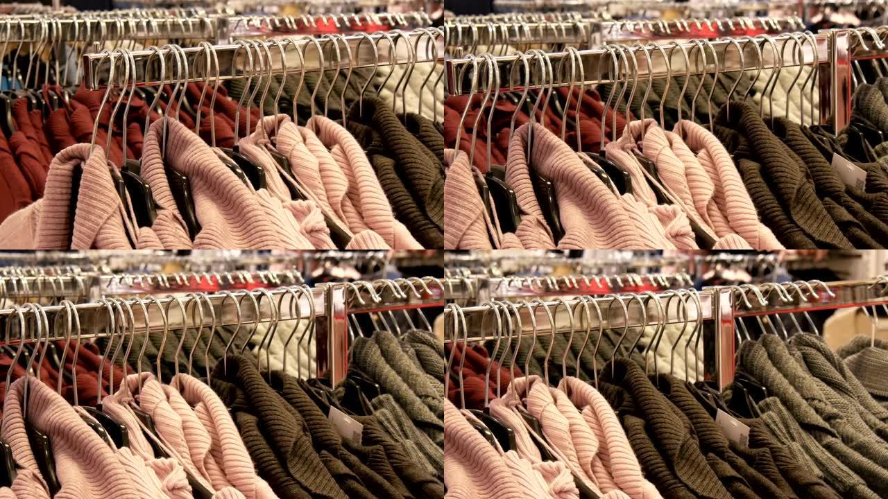 服装店购物中心或商场的衣架上悬挂着大量不同颜色的新款保暖时尚毛衣