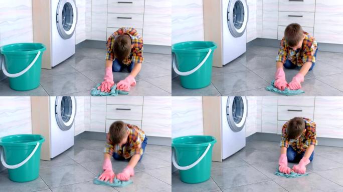 戴橡胶手套的疲倦男孩在厨房洗地板。