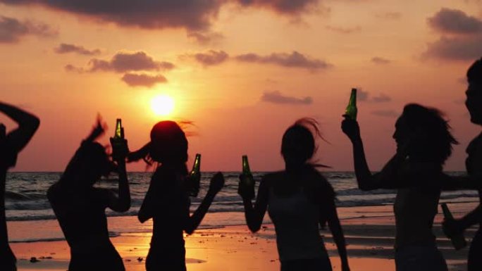 在日落背景下的海滩夏天，亚洲青少年团体一起跳舞和喝饮料的剪影。青年亚洲快乐情感和周年庆典。4k分辨率
