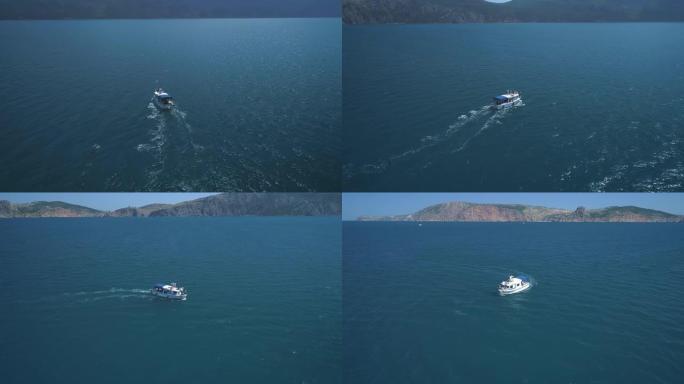 空中: 一群海豚在船旁边跳出水面。海豚在船前游泳。海豚追逐鱼。海边的暑假。